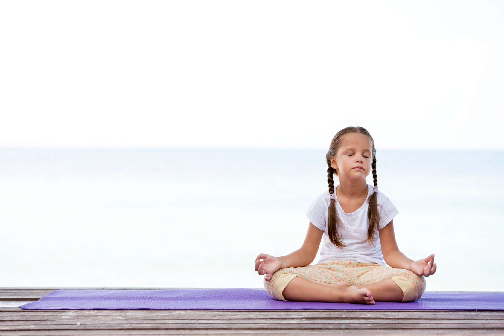 Child Meditating on Platform Outdoors